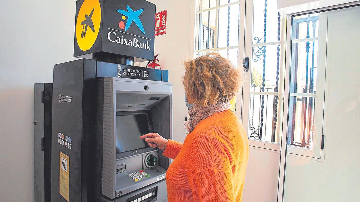 Una mujer saca dinero de uno de los cajeros instalados por la Generalitat en las localidades del interior.