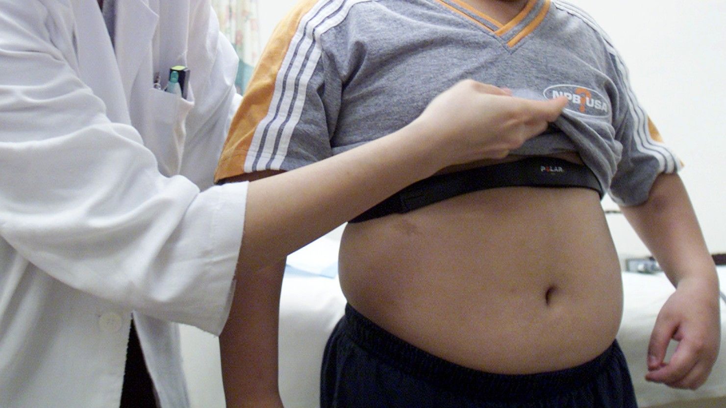 Una doctora muestra la barriga de un niño con sobrepeso