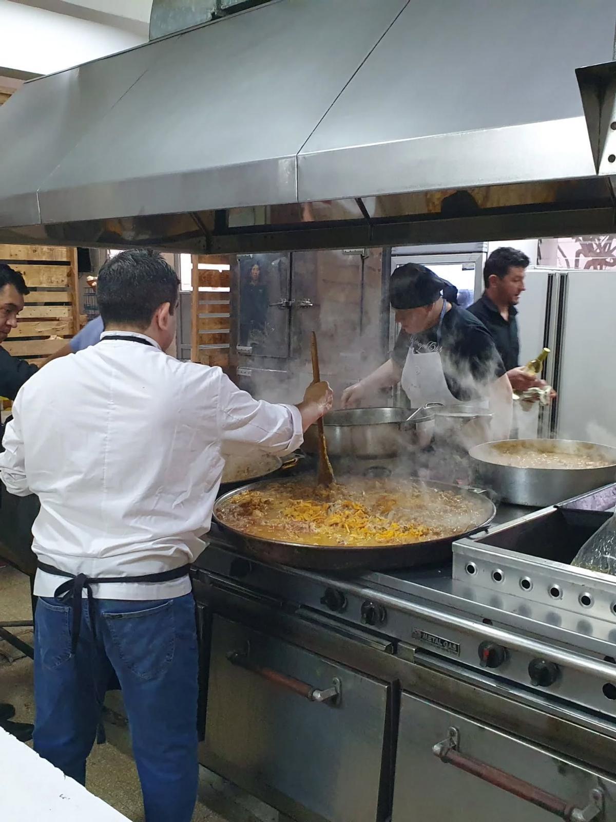 Los cocineros preparan la paella.