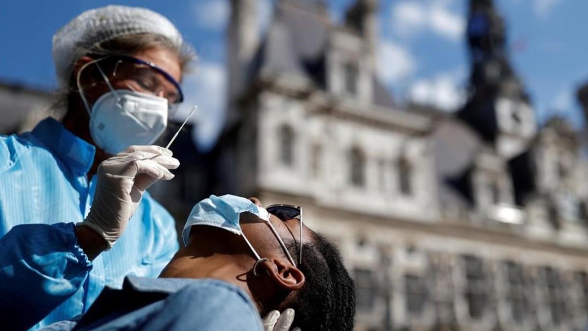 Un sanitario realiza una PCR frente al Ayuntamiento de París.