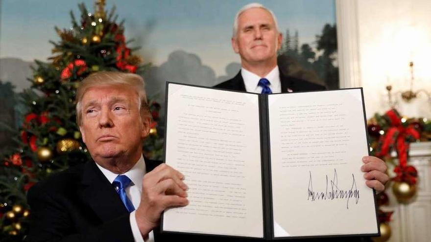 Trump muestra el texto del acuerdo, ya firmado, en presencia del vicepresidente, Mike Pence. // Reuters