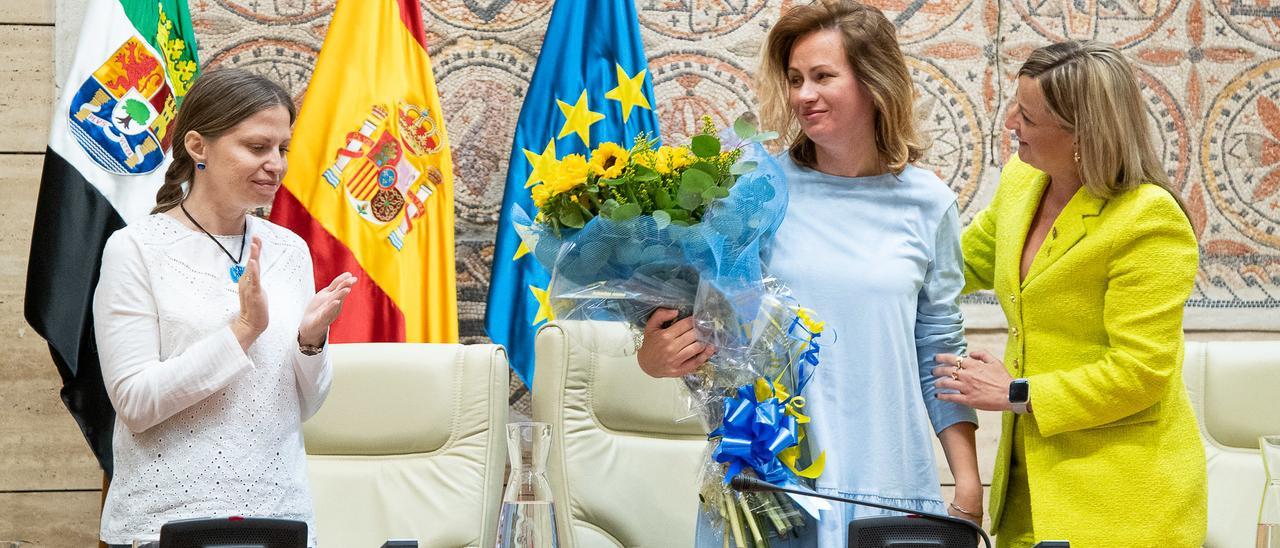 Oksana (centro) y Nadiia reciben un ramo de flores de manos de la presidenta de la Asamblea tras su intervención en el acto institucional.
