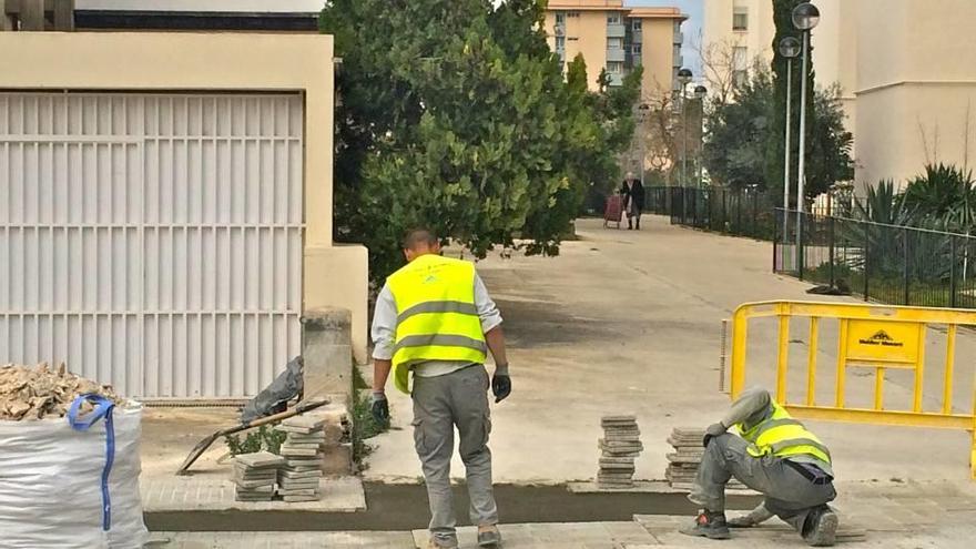 Dos operarios trabajan en la reparación de una acera en una calle de Palma.