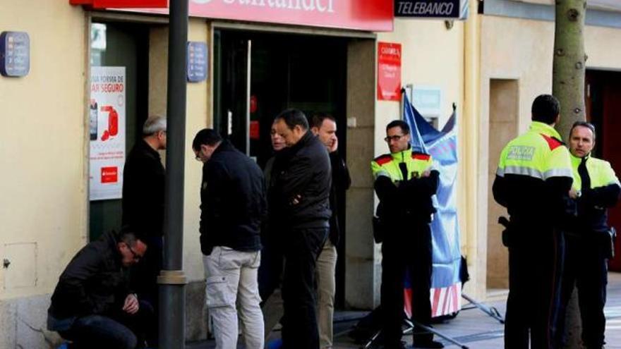 Agentes de los Mossos d&#039;Esquadra recogen pruebas a las puertas de la oficina del Santander. / efe