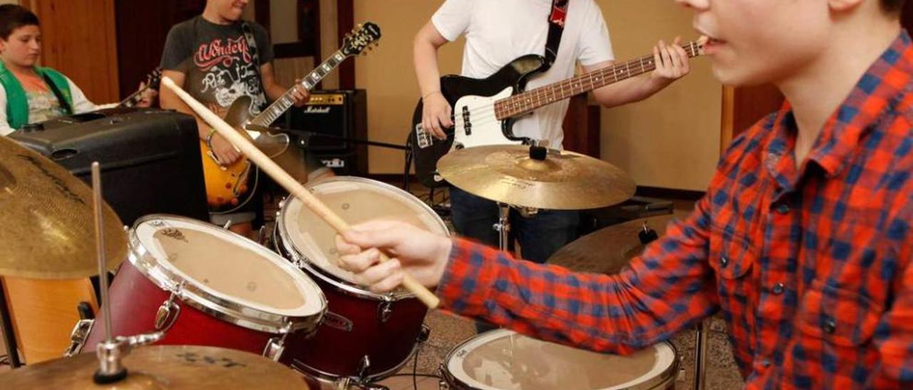 Alumnos del campamento tocan sus guitarras eléctricas acompañados de la batería.