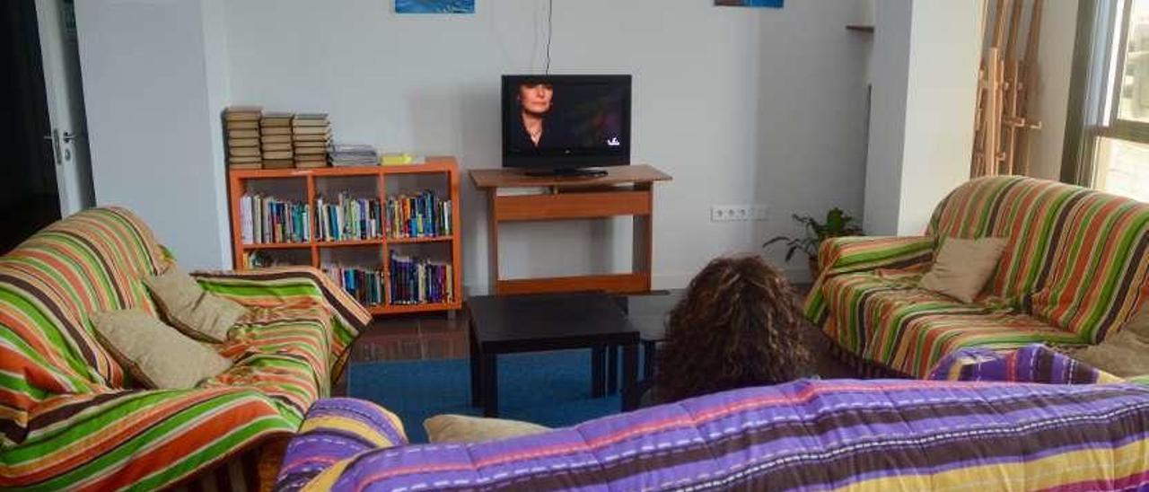 Una usuaria ve la television en la sala de estar, ocio e informática de Rexurdir en Pontevedra. // R.V.