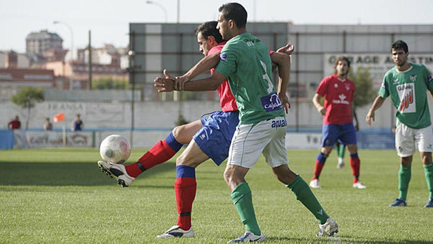 Un jugador del Benavente protege de espaldas el cuero ante la entrada de uno de los futbolistas del Guijuelo B.