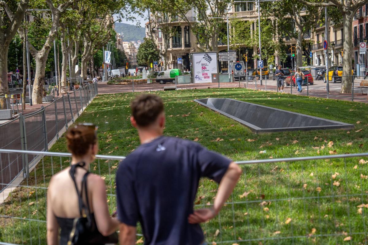 Una pareja observa 'Surco', la obra de Frederic Amat que representa el obelisco caído.