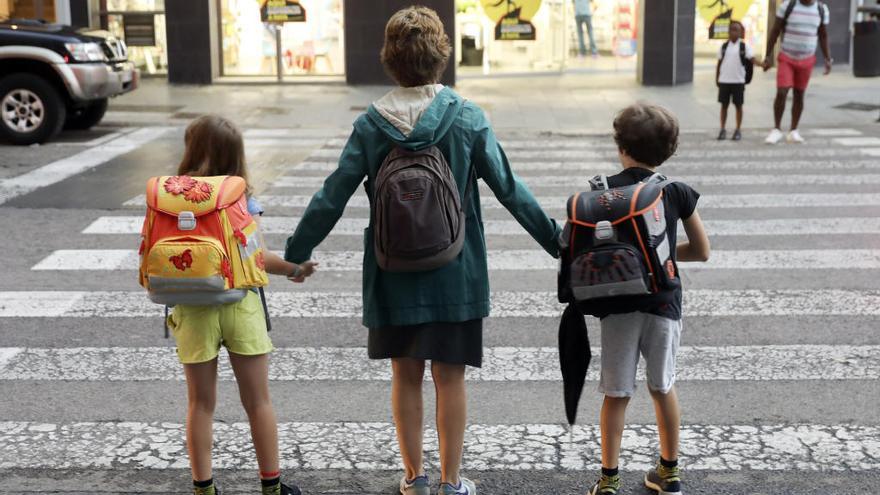 Una madre lleva a sus dos hijos al colegio durante el primer día de clase del presente curso escolar en València.