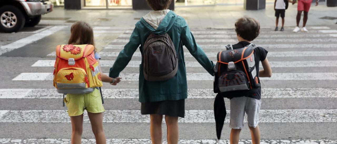 Una madre llevando a sus dos hijos al colegio en València.