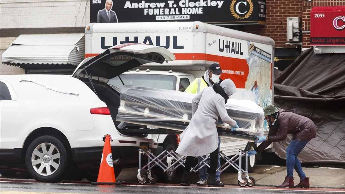 Estados Unidos supera los 100.000 muertos por coronavirus. En la foto, trabajadores de una funeraria de Brooklyn introducen un ataúd de una víctima de covid-19 en un coche fúnebre.