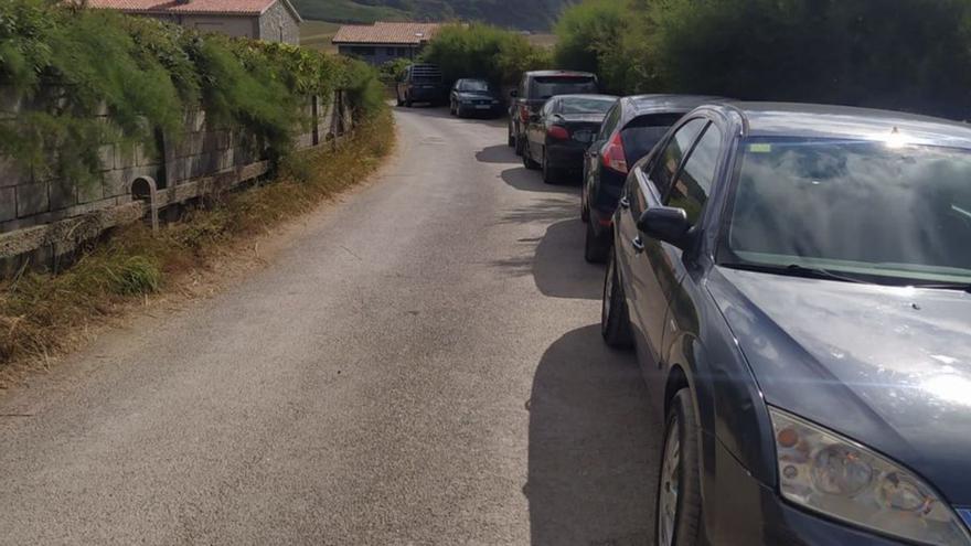 Una fila de coches, ayer, aparcados sobre el vial de acceso a la playa.