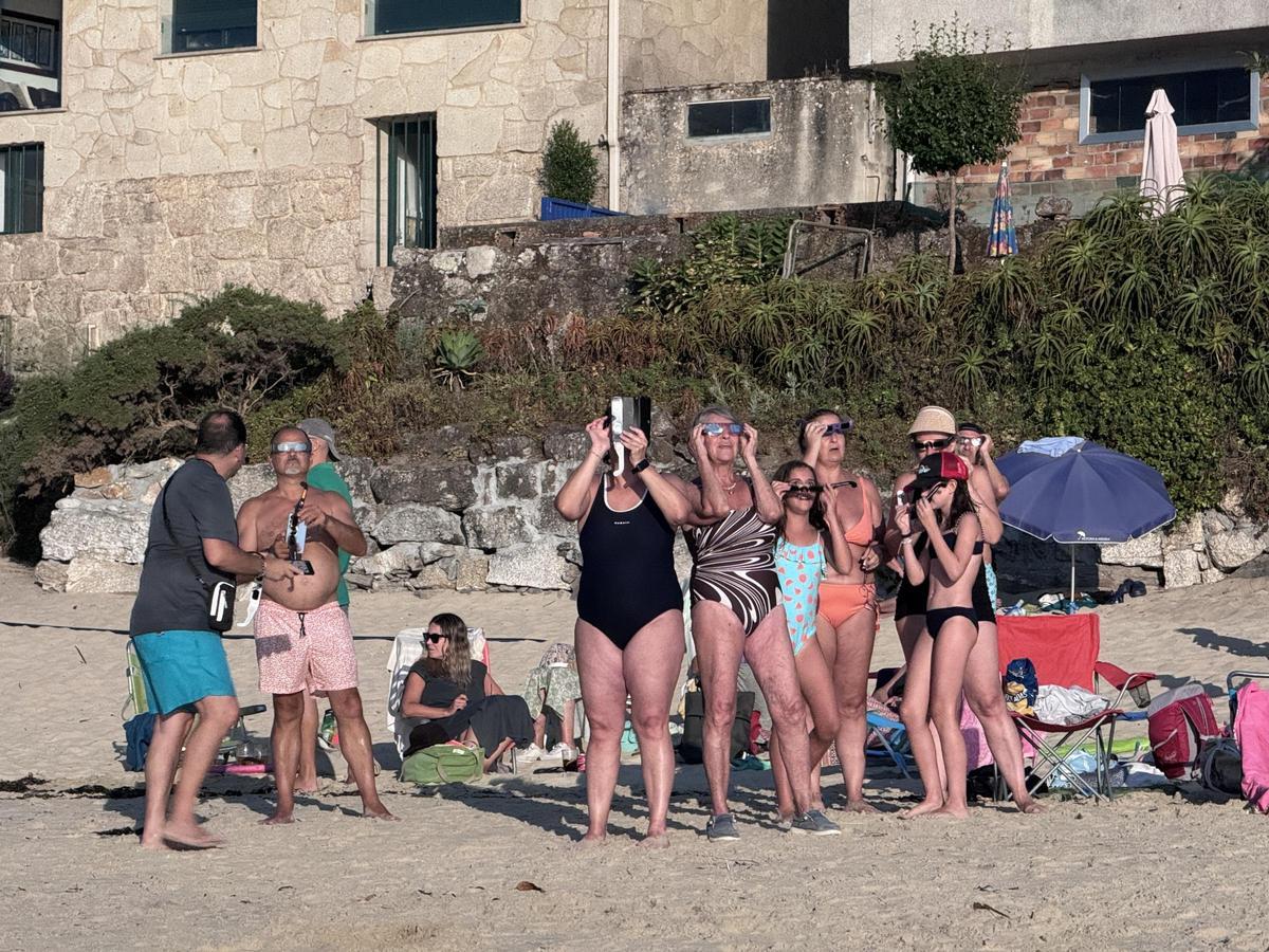 Bañistas y vecinos siguen el eclipse solar desde Loureiro. Bañistas y vecinos siguen el eclipse solar desde Loureiro.