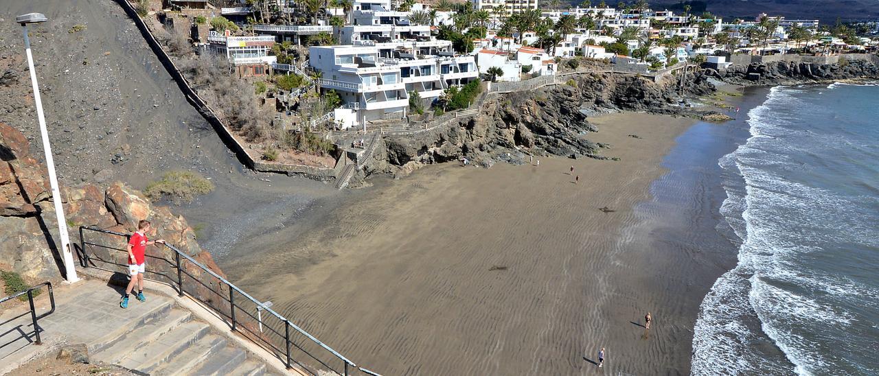 En primer plano, la escalera de la playa de Morro Besudo y al fondo el paseo marítimo.