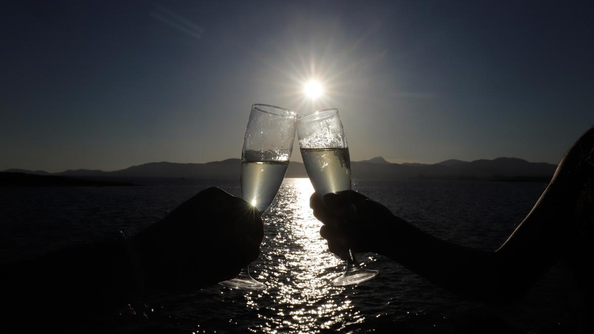 Ein Paar stößt bei Sonnenuntergang in der Bar Purobeach in Cala Estancia am Strand Playa de Palma mit Champagner an
