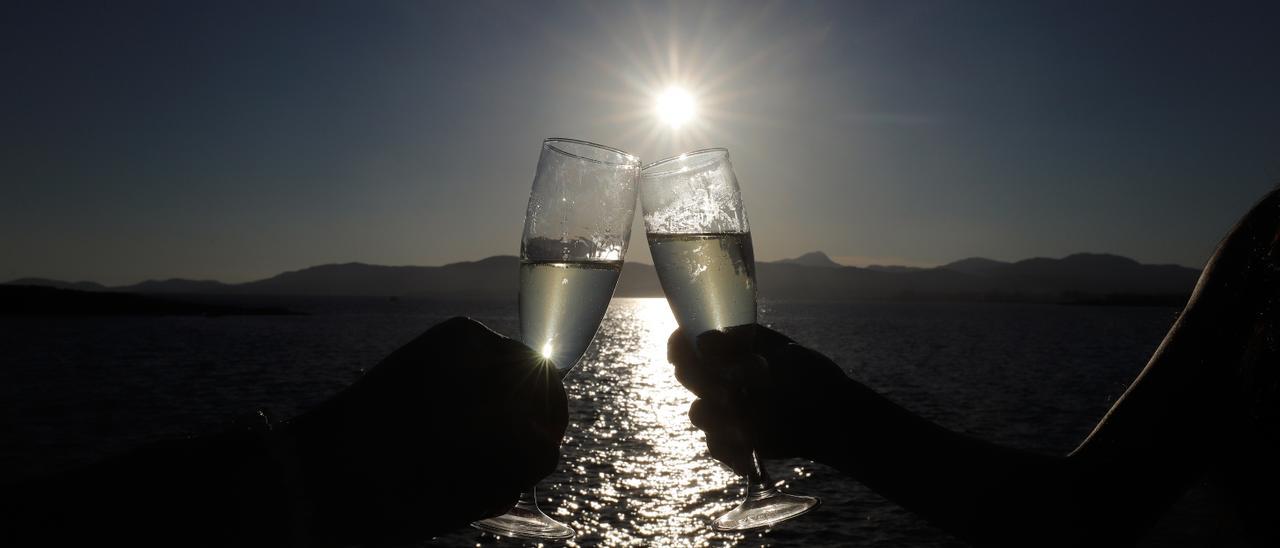 Ein Paar stößt bei Sonnenuntergang in der Bar Purobeach in Cala Estancia am Strand Playa de Palma mit Champagner an