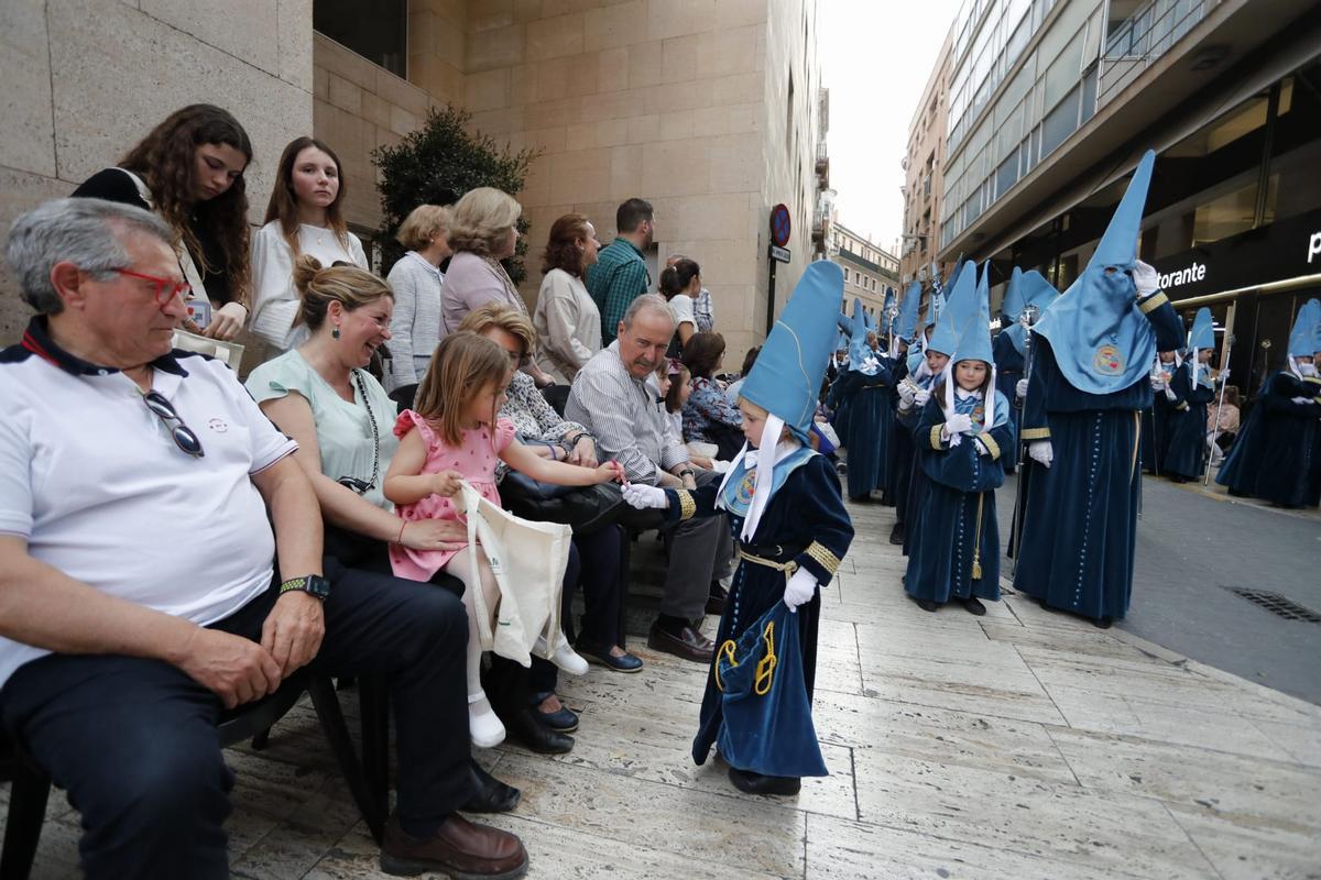 Un jovencísimo nazareno da caramelos a una niña este Viernes de Dolores en Murcia.