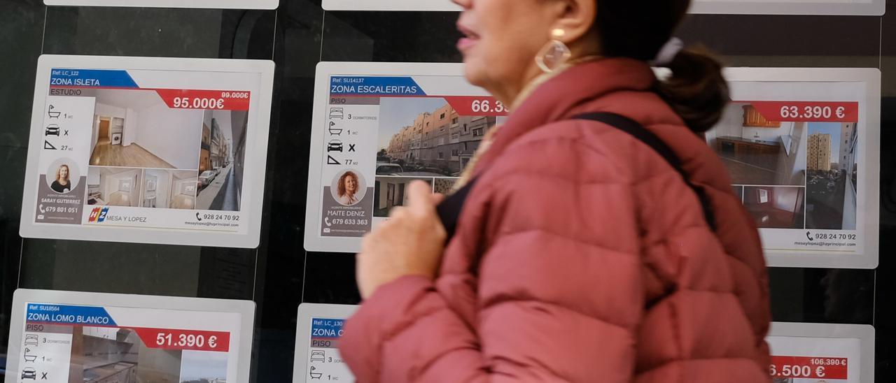 Una mujer pasa por delante de una inmobiliaria.