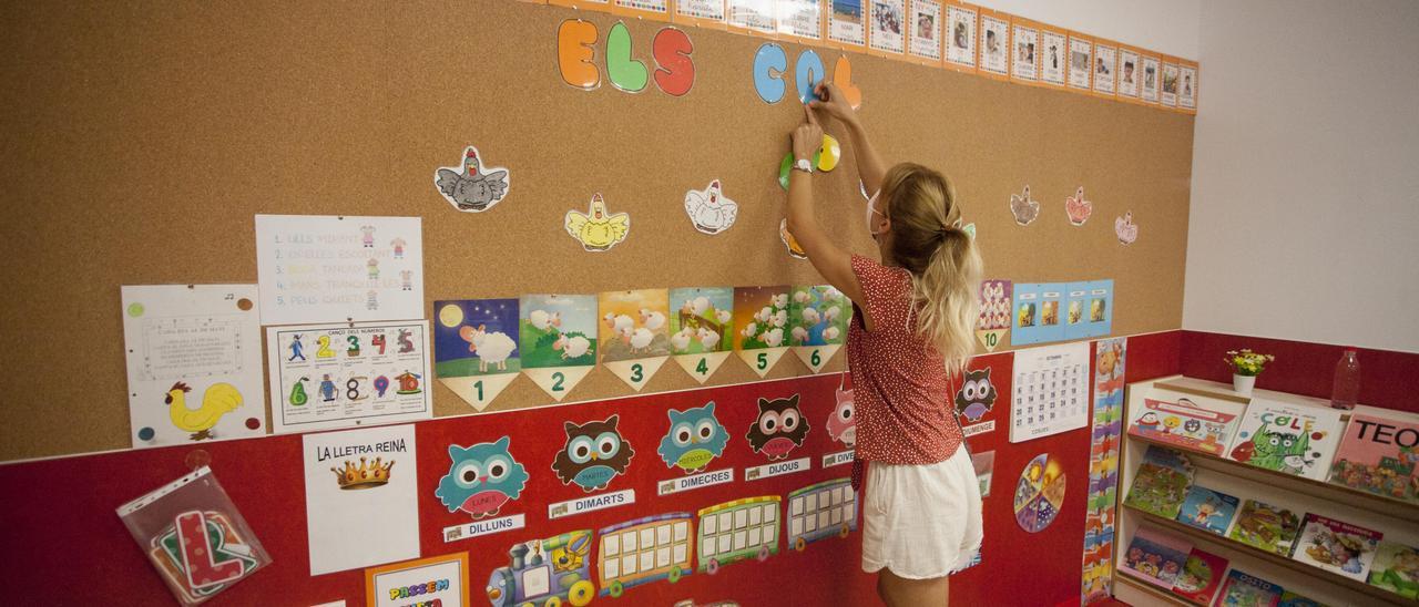 Una profesora decora una clase, al inicio de curso.