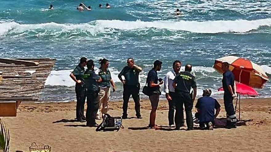 Els serveis de socorrisme, amb la víctima encara a la sorra, i al fons el mar amb fort onatge.