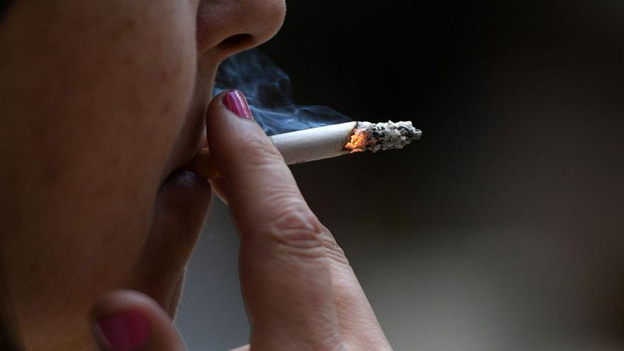 Una mujer fuma un cigarrillo.