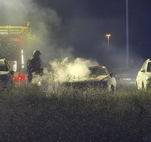 Momento en el que los bomberos sofocan el fuego de un vehículo en la barriada de Suerte de Saavedra, en Badajoz.