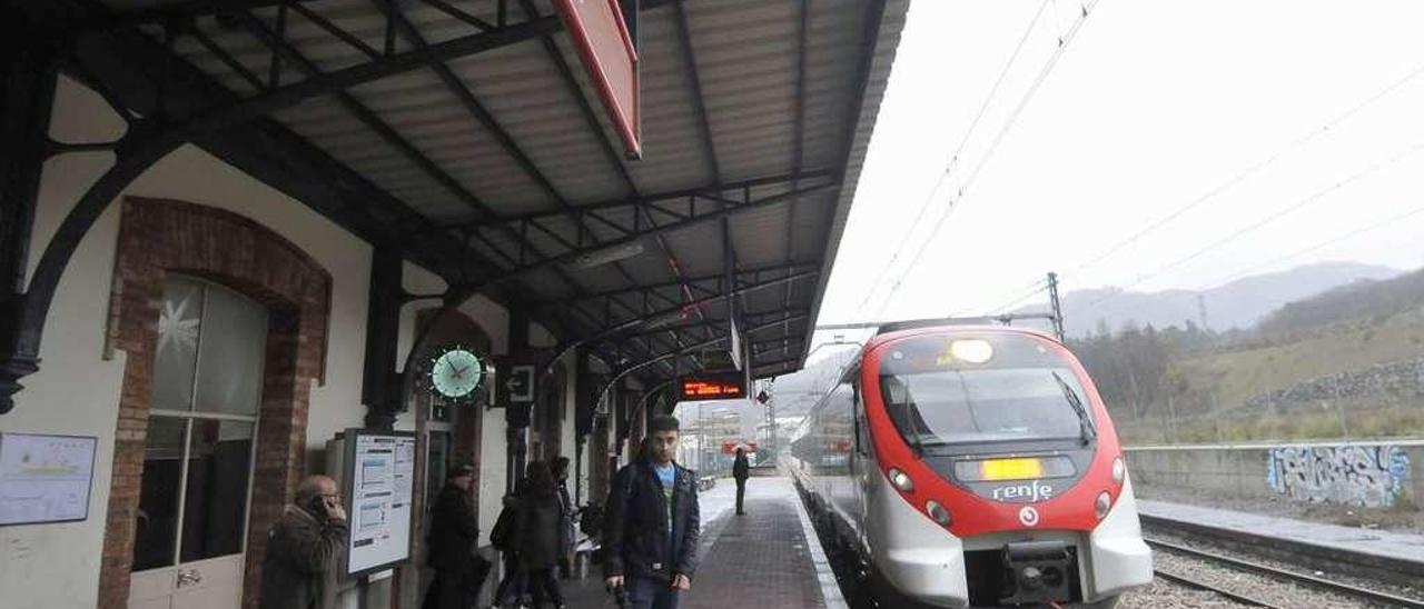Viajeros esperando al tren en dirección Oviedo en la estación de Sama.