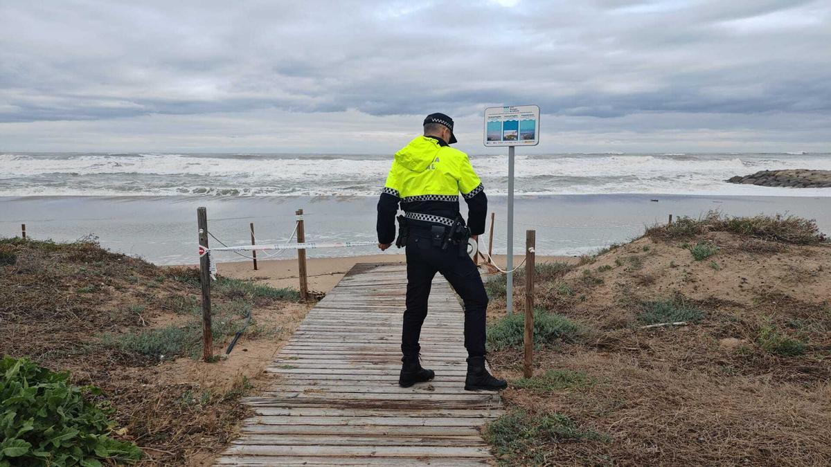 Un policía local cierra un acceso al mar.