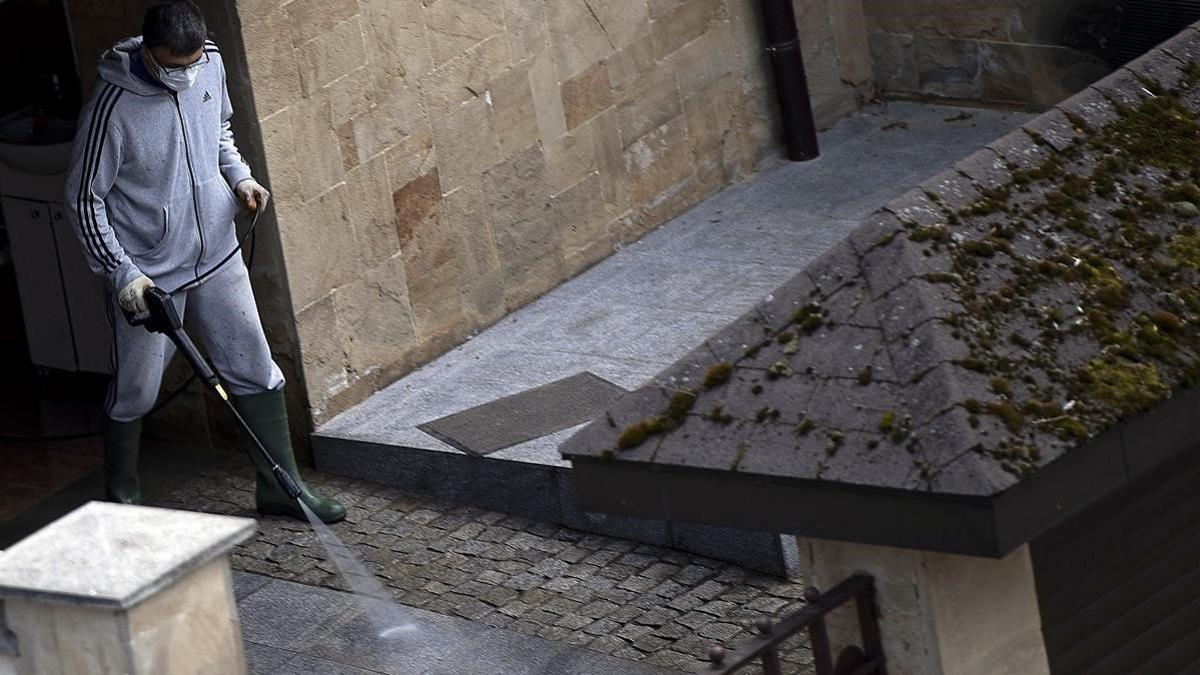 Un hombre con mascarilla limpia el patio de su casa en Sofía, el 29 de marzo del 2020