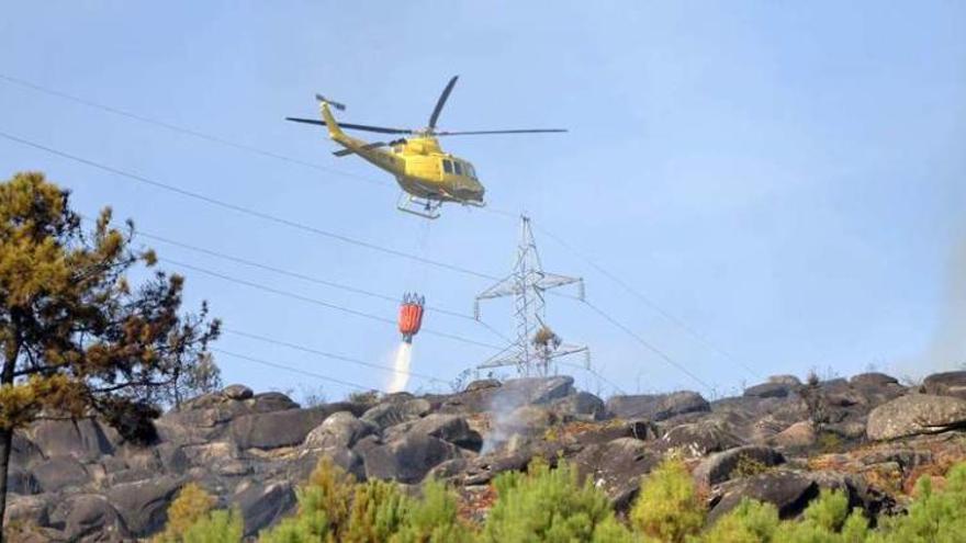 El helicóptero que participó en la extinción lanza agua sobre el fuego ya controlado. // Gustavo Santos