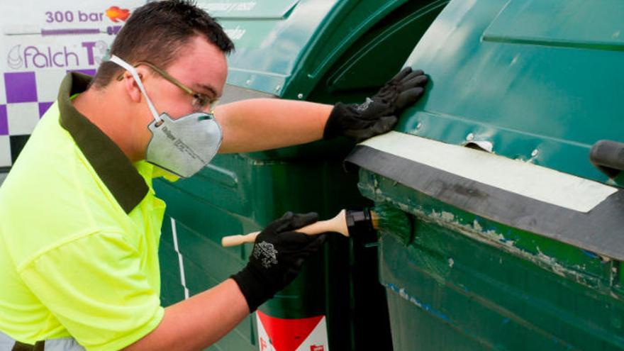 Un hombre con discapacidad pinta un contenedor de basura como parte de su ejercicio laboral.