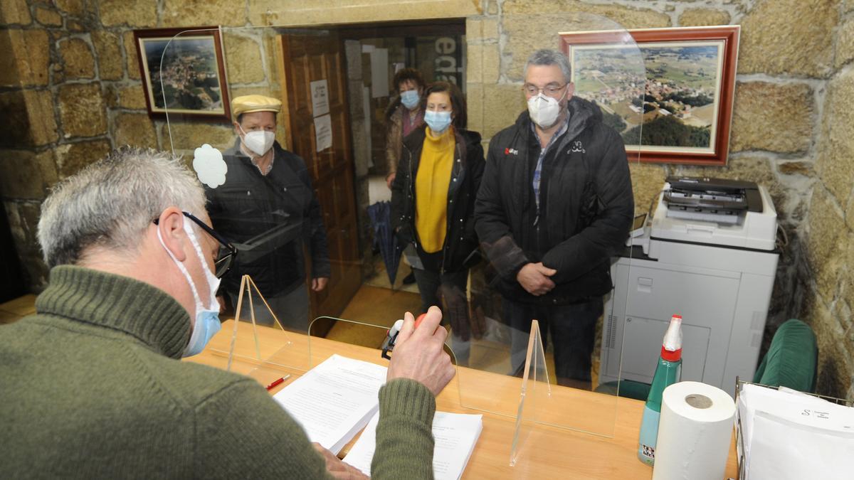 Un empleado atiende a vecinos en una oficina municipal.