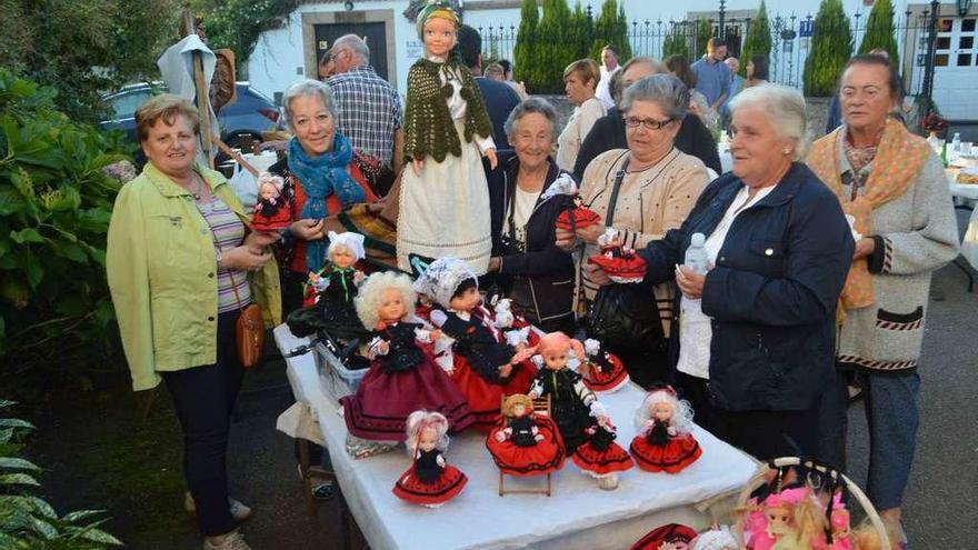 La artesana de muñeques asturianes Charo Espiniella y vecinas viendo sus trabajos.