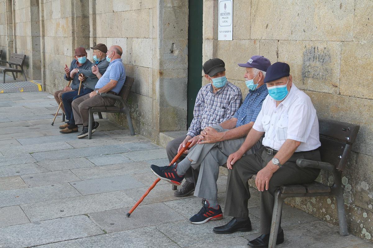 Seis hombres sentados en unos bancos con mascarillas Seis hombres sentados en unos bancos con mascarillas