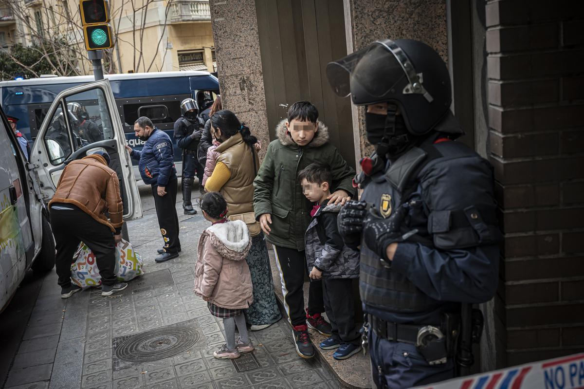 Nicolai, de diez años, abraza a su hermano después que los Mossos les expulsaran del banco abandonado donde vivían y mientras su padre y tíos cargan las furgonetas con todas sus pertinencias.