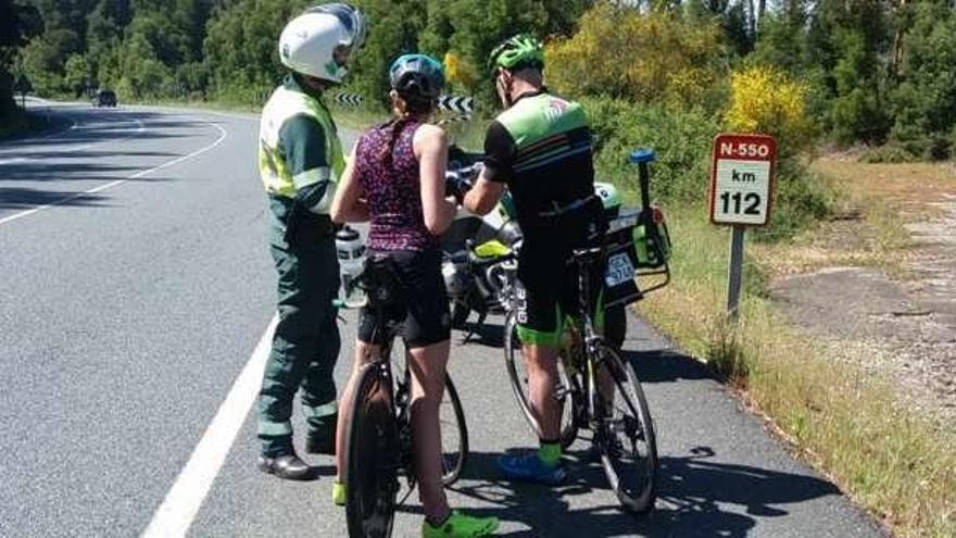 Agentes de la Guardia Civil de Tráfico, entregando folletos informativos a dos ciclistas. // Guardia Civil