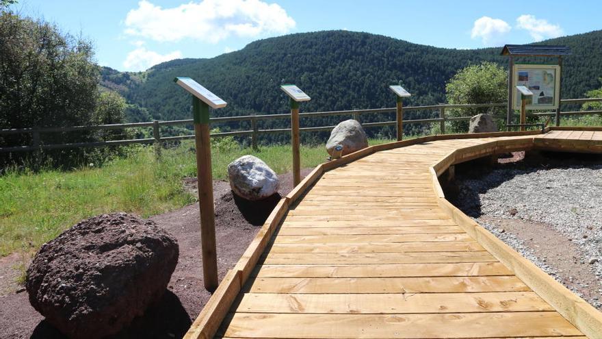 Passera de fusta i una de les pedres exposades al Jardí de roques de Rubió.