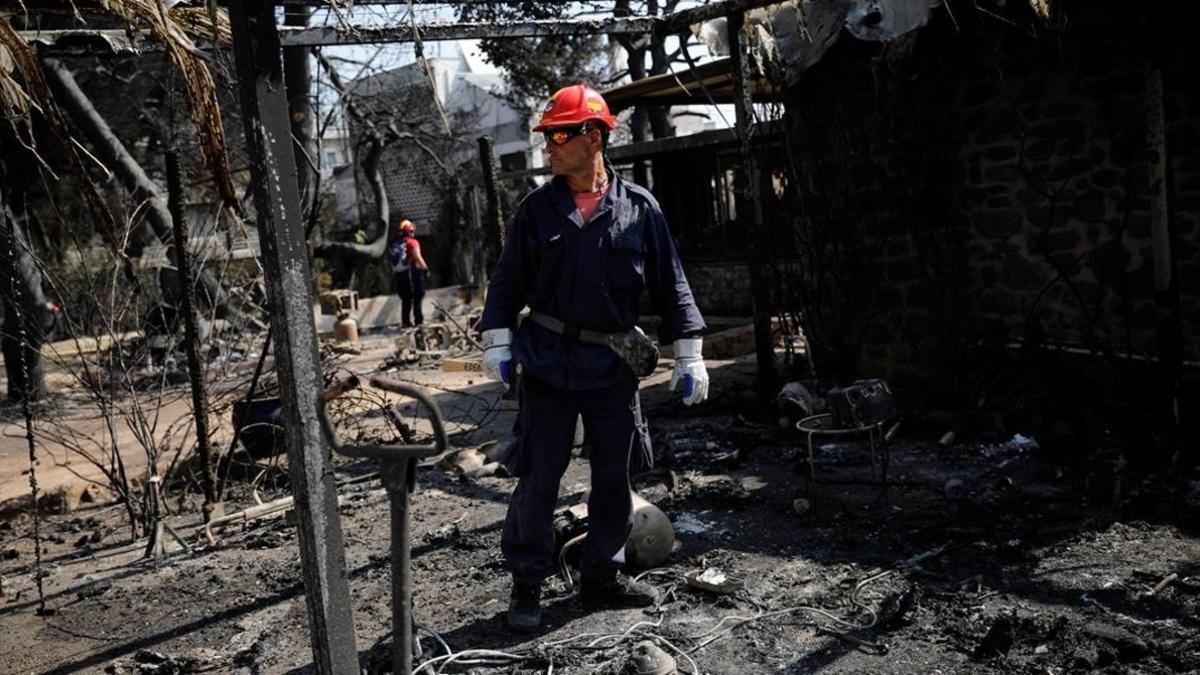 Un bombero inspecciona una de las viviendas quemadas por las llamas en la ciudad de Mati, próxima a Atenas.