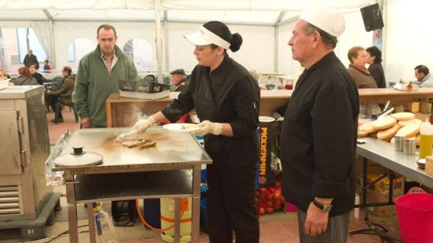 Una cocinera «trabaja» en la plancha varias navajas en la carpa de la Feria del Marisco.