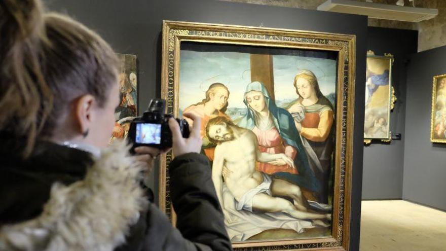 Una mujer fotografía una de las obras expuestas en el Diocesano