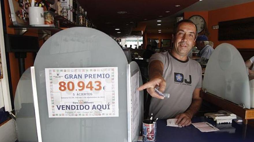 El propietario del bar «Crespo» muestra el cartel con el número ganador.