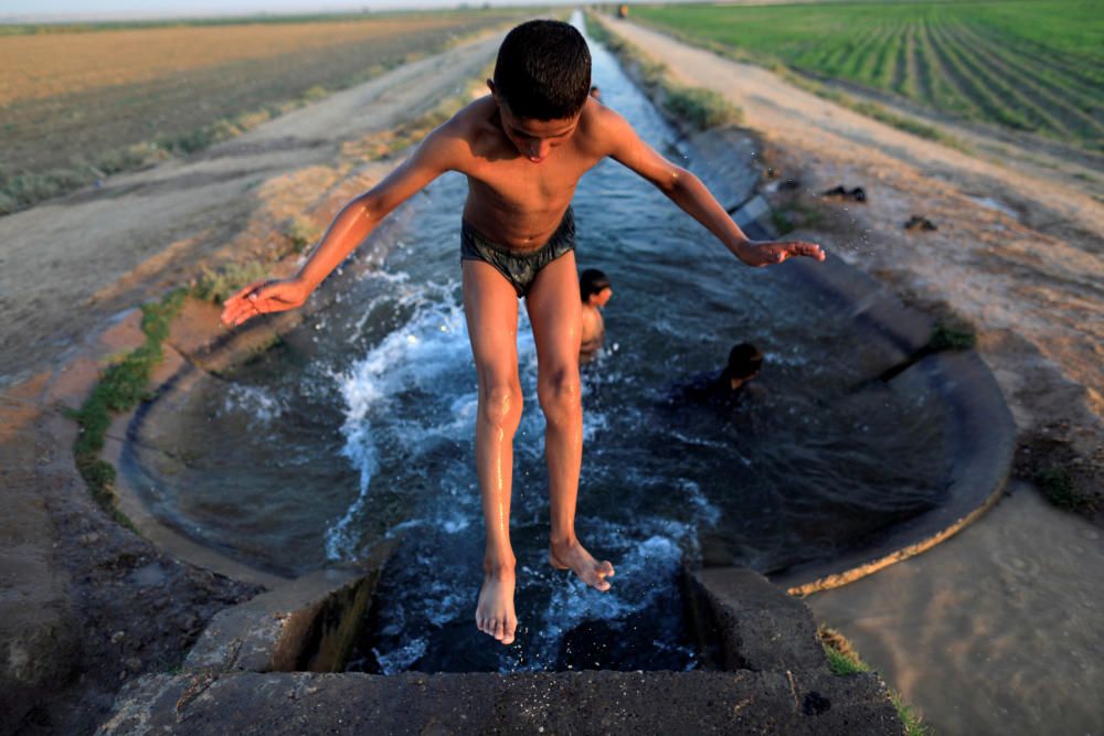 A boy cools off in an irrigation canal on the ...