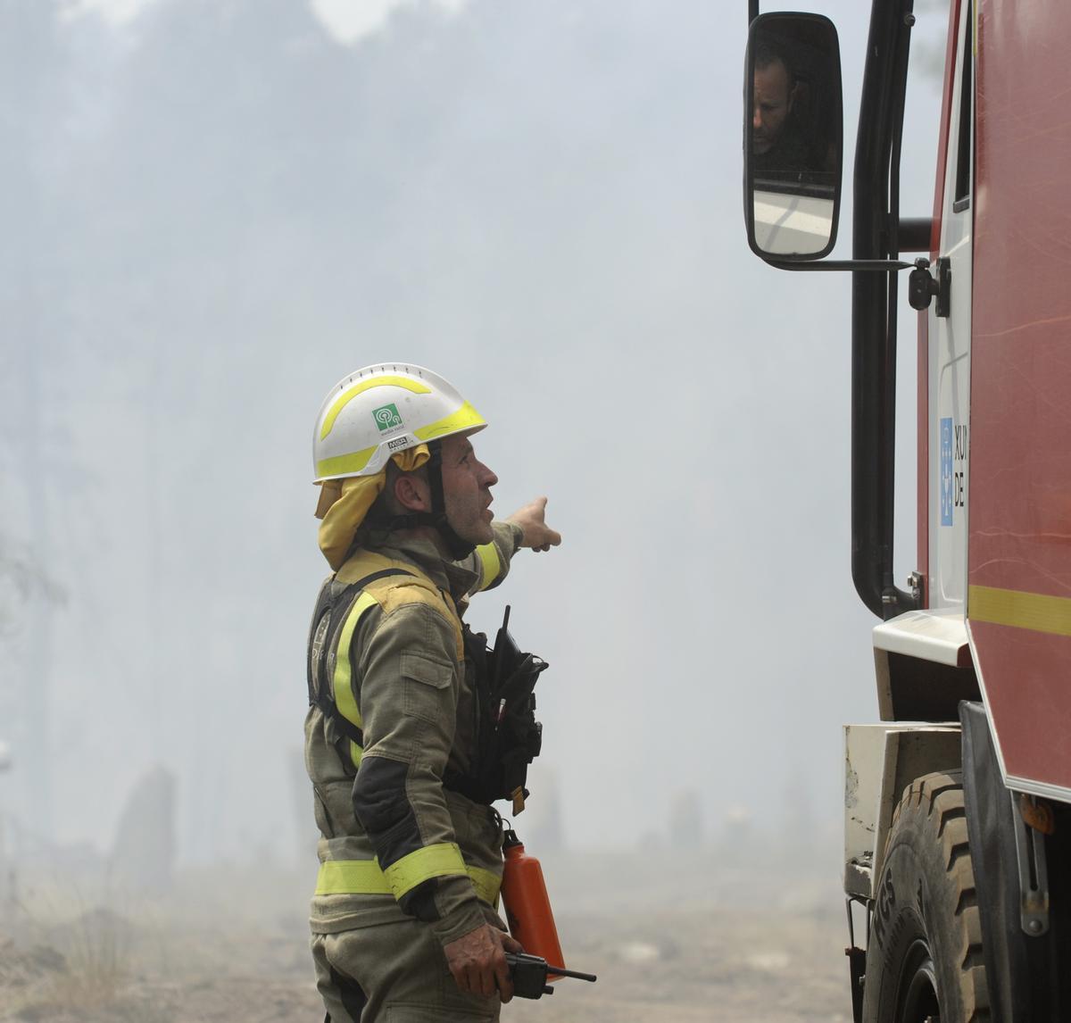 Un bombero charla da instrucciones a un compañero, en el incendio de Guillar, en Rodeiro.