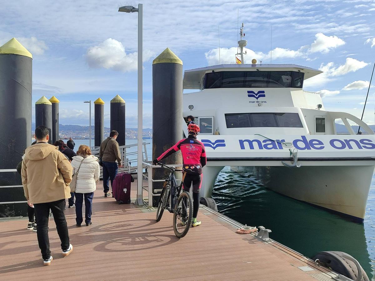 Viajeros del transporte de ría ante un barco de Mar de Ons en Cangas a comienzos de este enero