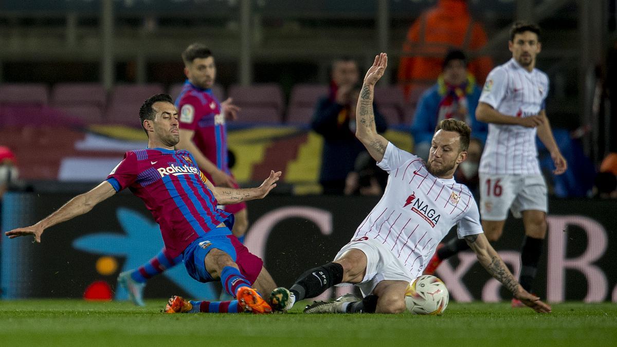 Busquets y Rakitic pelean un balón desde el suelo