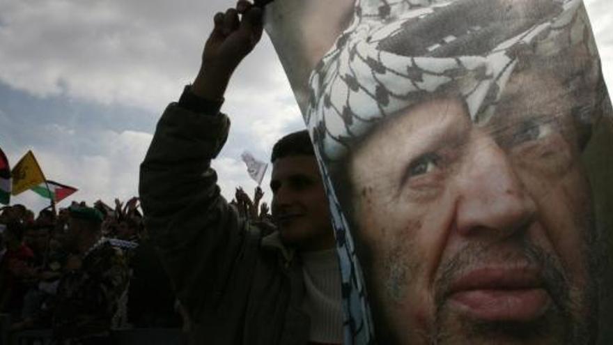 Un palestino sostiene una bandera con la imagen de Arafat.