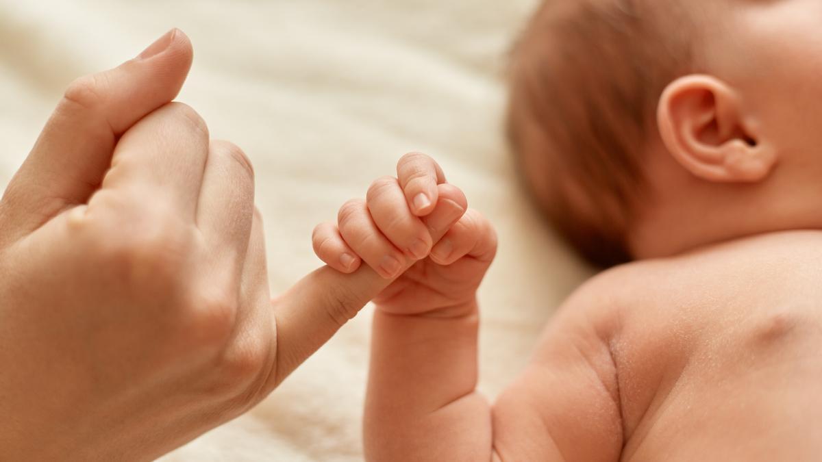 Un nadó subjecta amb una mà el dit d'un adult