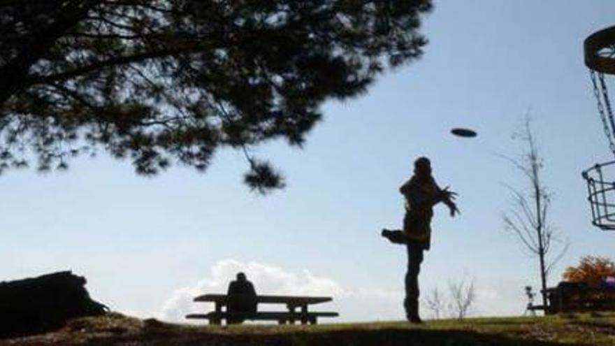 A la izquierda, Fernando López-Cancio realiza un &quot;putt&quot; (lanzamiento de cerca) en el parque Purificación Tomás, en Oviedo. Junto a estas líneas, Carlos Álvarez Río, capitán de la selección española de disc-golf.