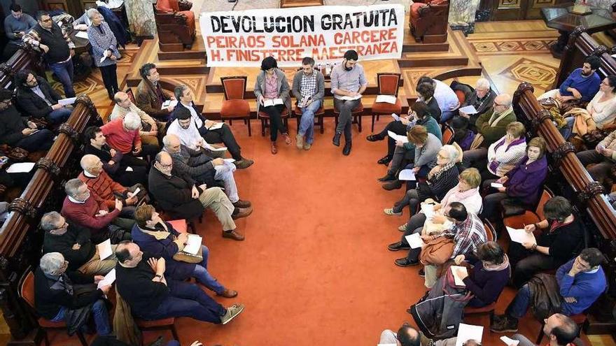 El alcalde y dos ediles, en el centro, en el salón de plenos con miembros de la Comisión pola Defensa do Común.