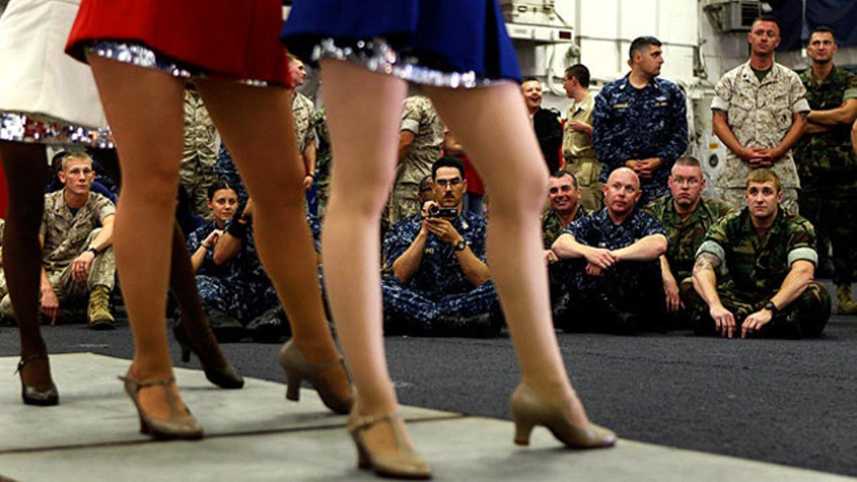 Un grup de reclutes de la marina dels Estats Units observa la suggerent actuació de dues ballarines en la coberta del vaixell d’atac amfibi Iwo Jima.